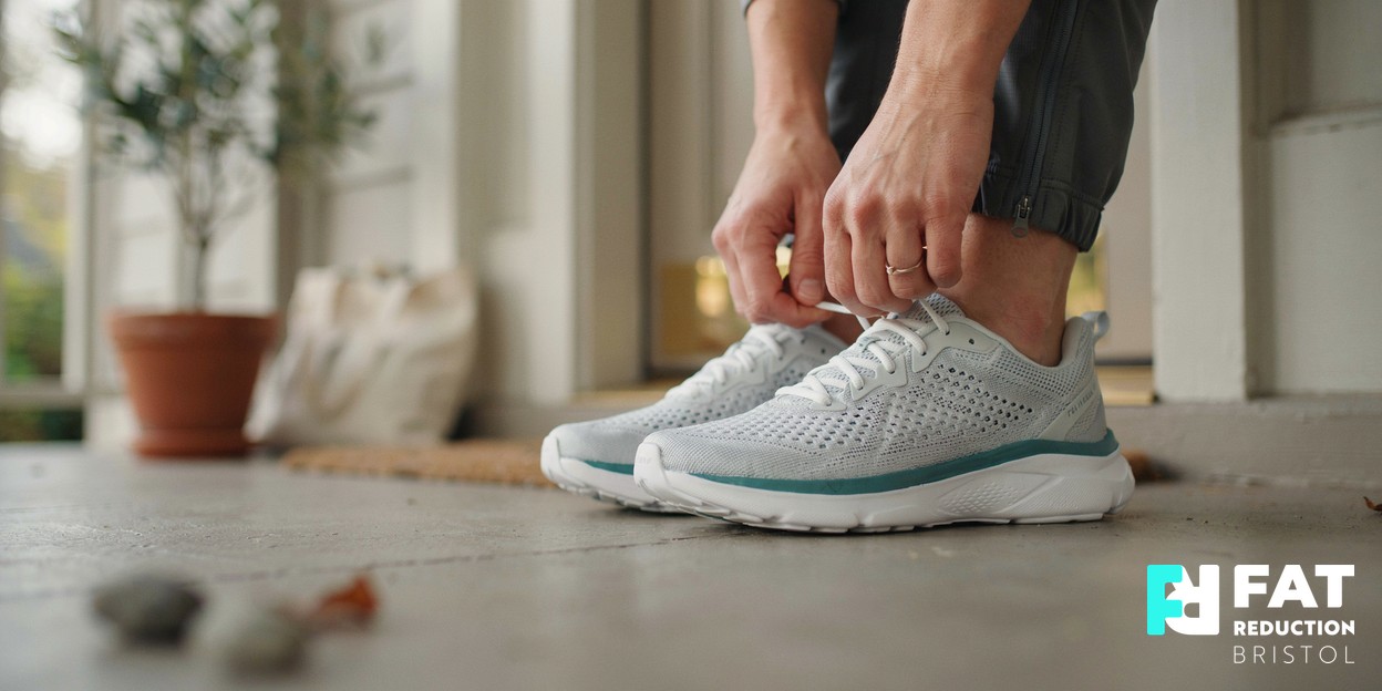 Close-up of a person’s hands lacing up running trainers on a doorstep in soft morning daylight